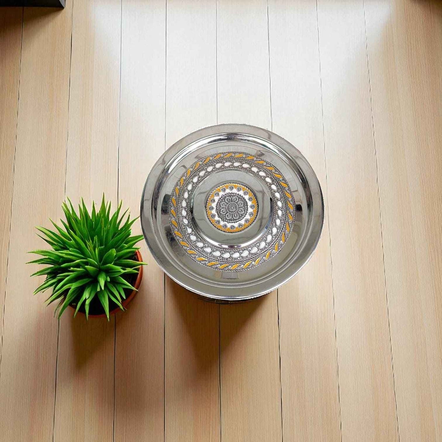 Antique Stainless Steel Pawali 7 litre with intricate gold and silver pattern on wooden floor next to green potted plant