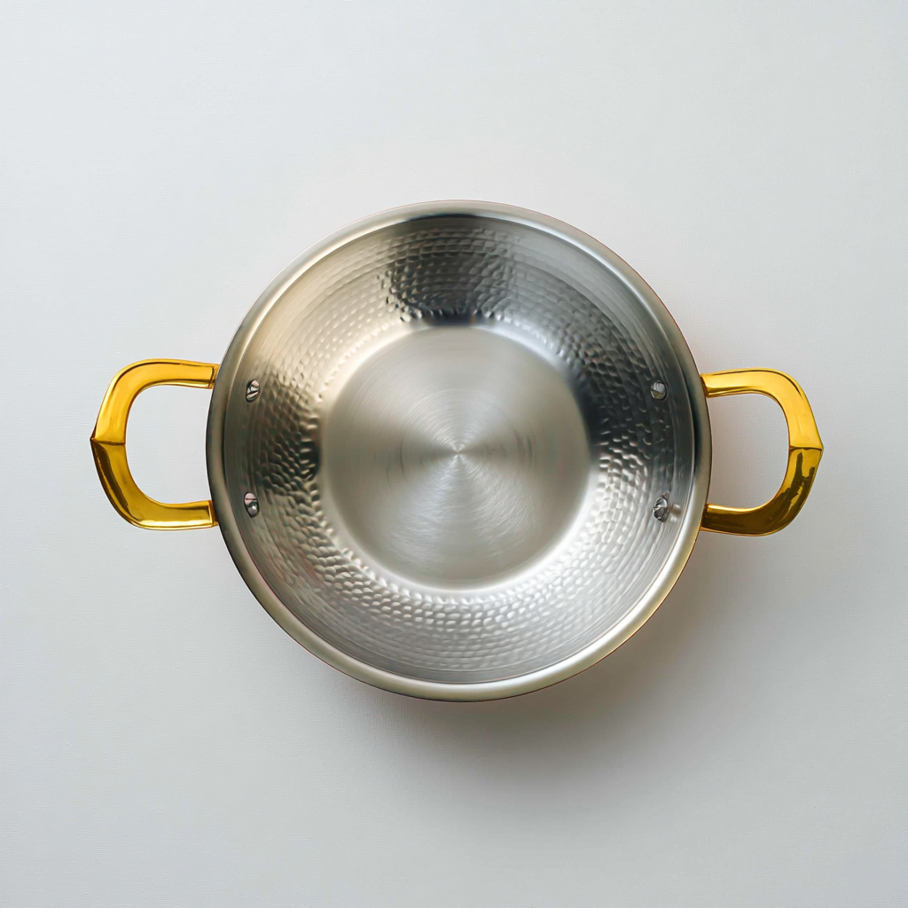 Overhead shot of brass kadai for cooking showing tin-coated interior and dual handles