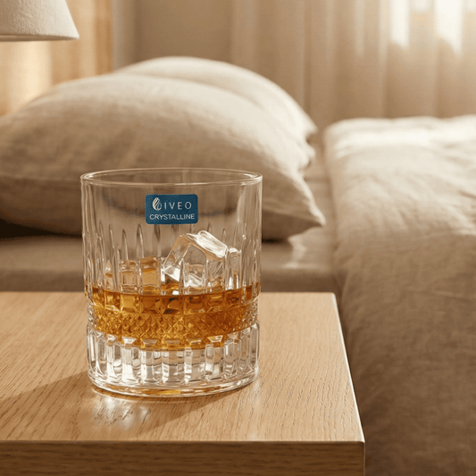 Iveo Crystalline Marvel Crystal Whisky Glass with Ice on a Wooden Table Next to a Couch