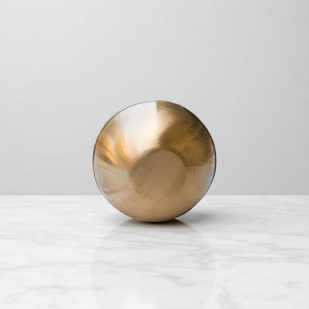 Small smooth kansa wand with flat base for kansa wand massage and foot therapy placed on marble