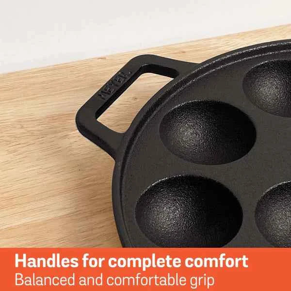 Meyer Cast Iron Appam Pan with four round molds and comfortable handle on wooden surface
