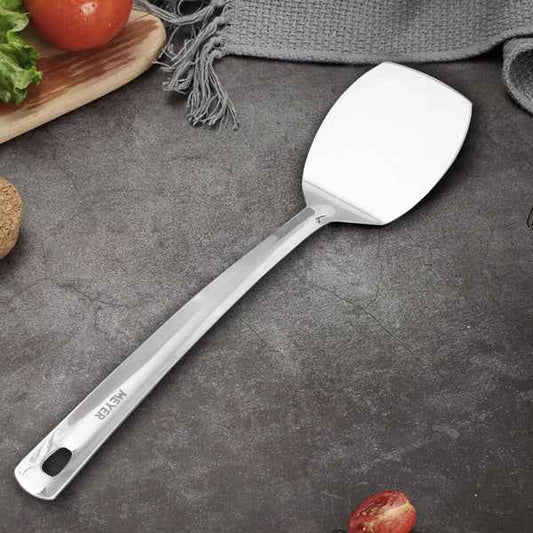 Meyer Stainless Steel Turner with a smooth handle and flat blade on a dark kitchen countertop