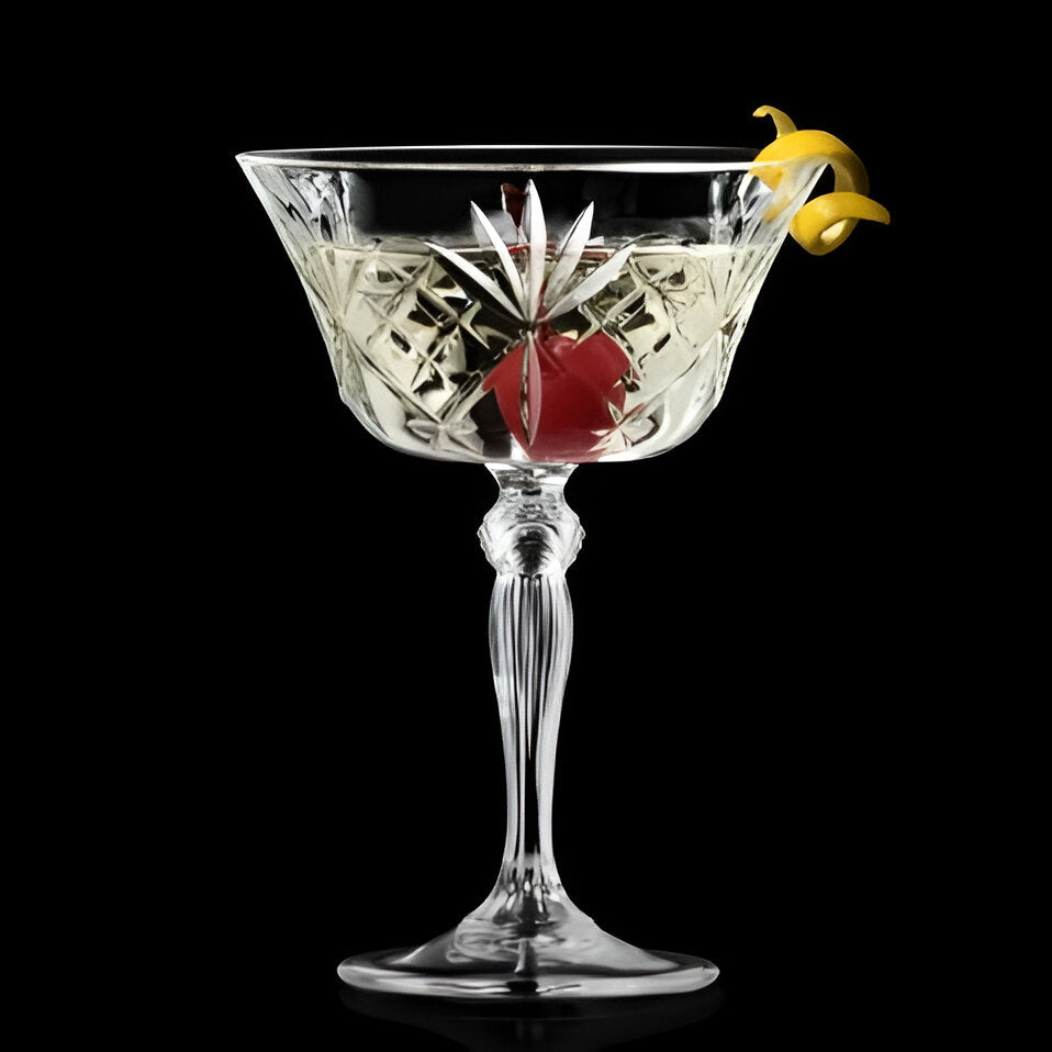 RCR Melodia Champagne Coupe Glass with cocktail and garnish on a sleek black background, elegant serving