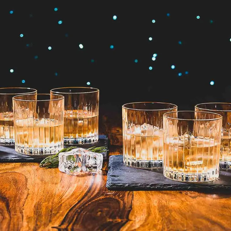 RCR Timeless whiskey glasses set on wooden table with whiskey and ice, perfect for elegant sipping