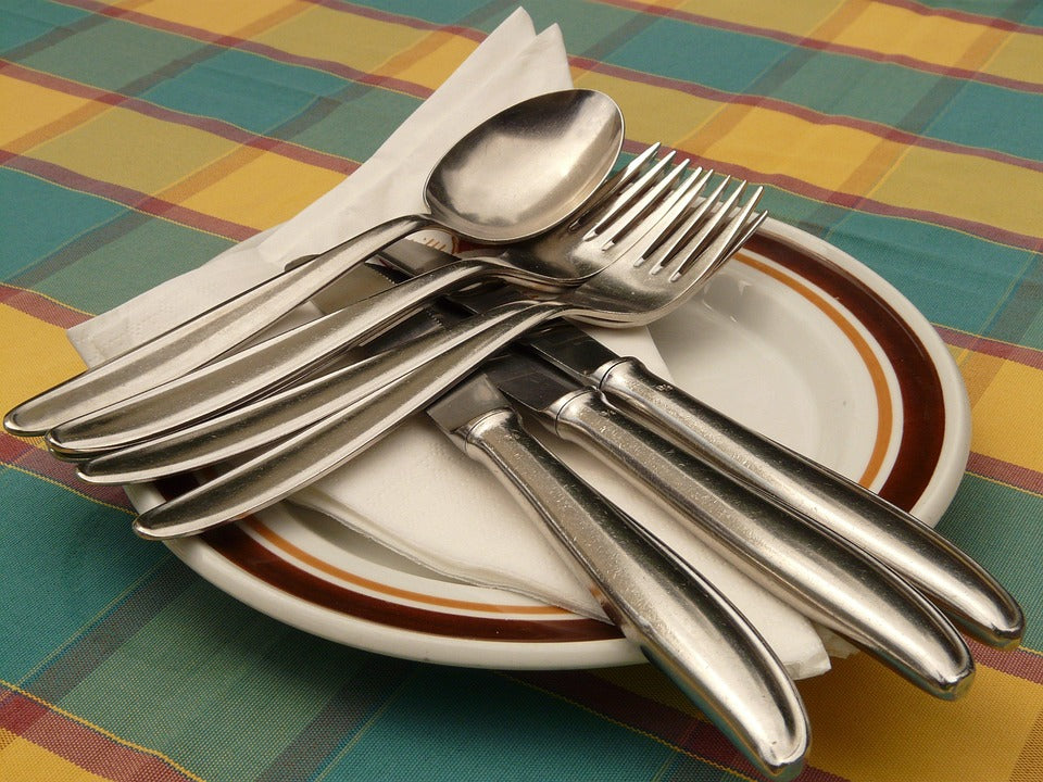 Elegant stainless steel cutlery set arranged on a plate with napkin, perfect for dining occasions