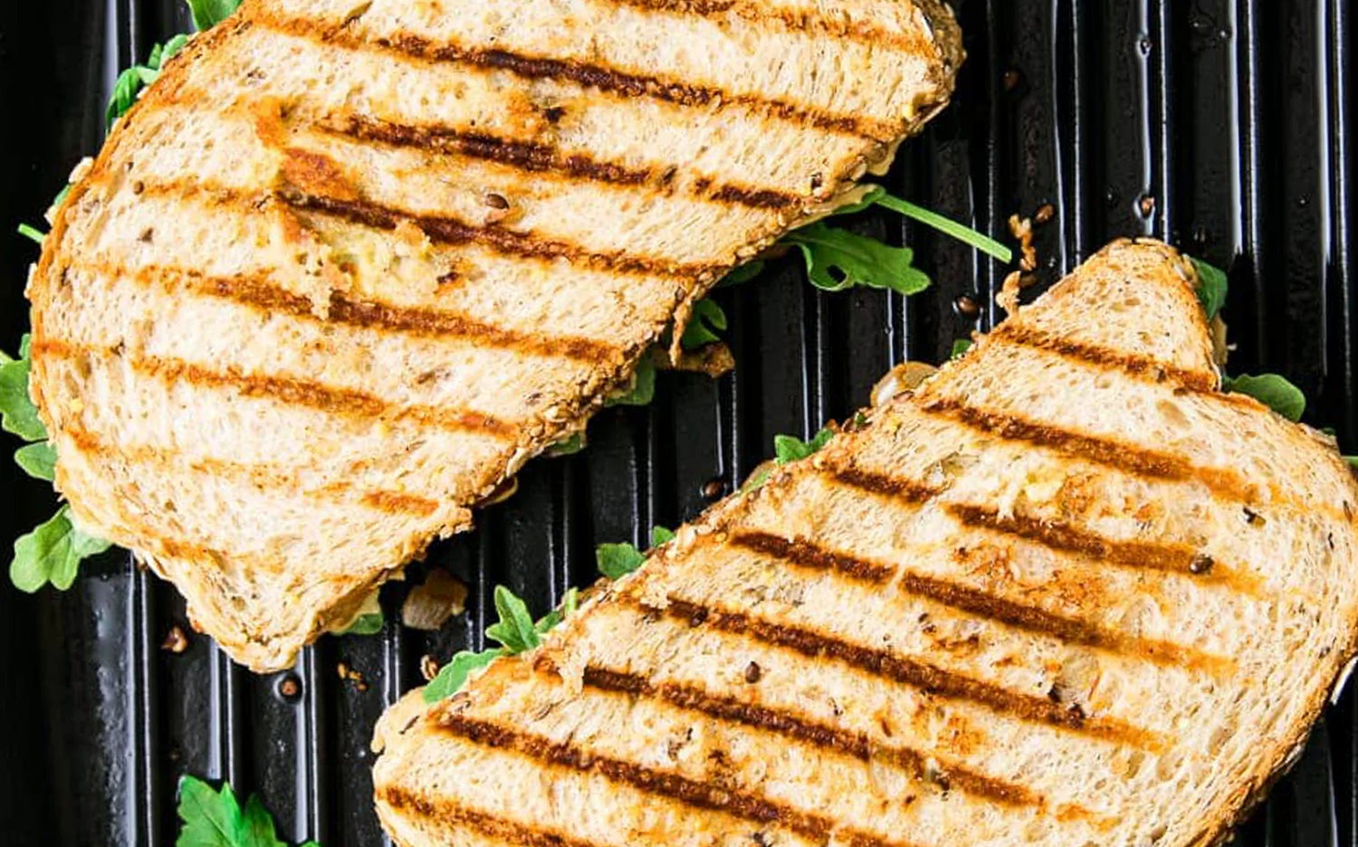 Two grilled bread slices on a Meyer cast iron grill pan 25cm with visible grill marks.