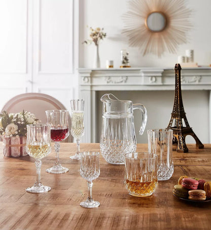 Cristal D'Arques Longchamp Series cocktail glasses set on a wooden table with drinks and a decorative pitcher