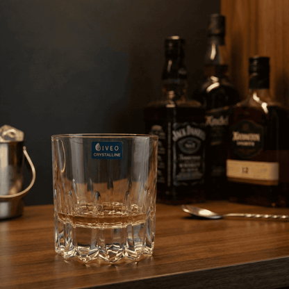 Iveo Crystalline Grace Crystal Whisky Glass on a wooden bar counter surrounded by various whisky bottles