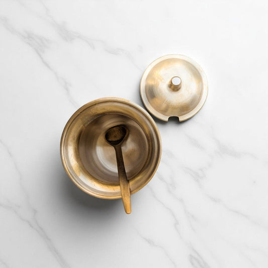 Kansyam bronze ghee loti with lid spoon shown open on white marble surface for Pooja use