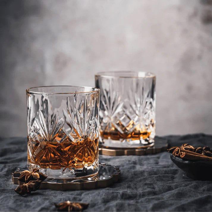 RCR Melodia DOF whiskey glasses with whiskey on a dark background with spices and coasters.