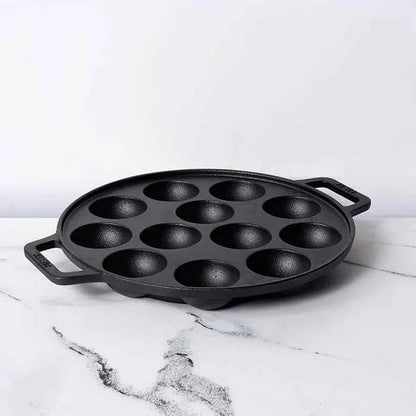 Meyer Cast Iron Appam Pan with twelve round molds and dual handles on white marble surface