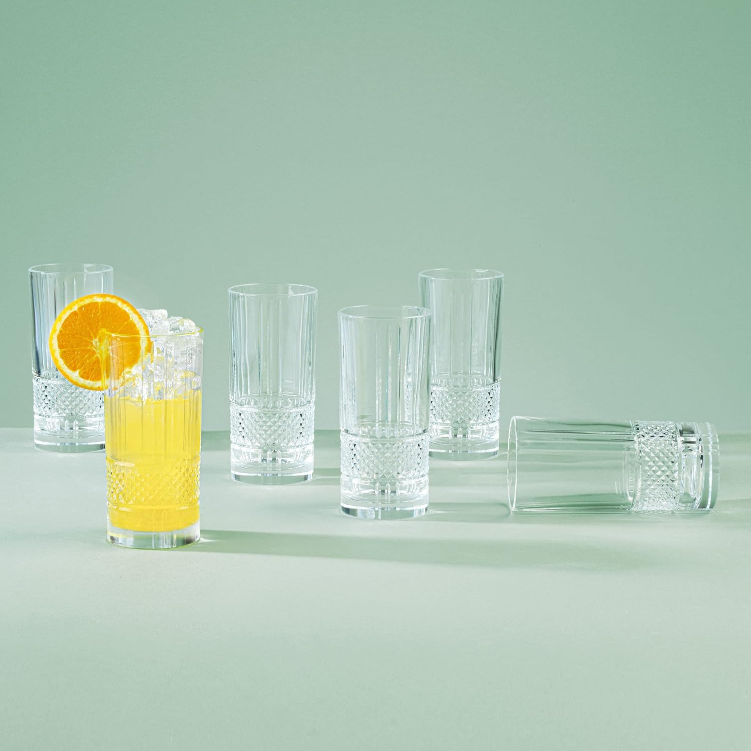 RCR Brillante cocktail glasses set displayed with refreshing drinks and garnishes on a soft green background