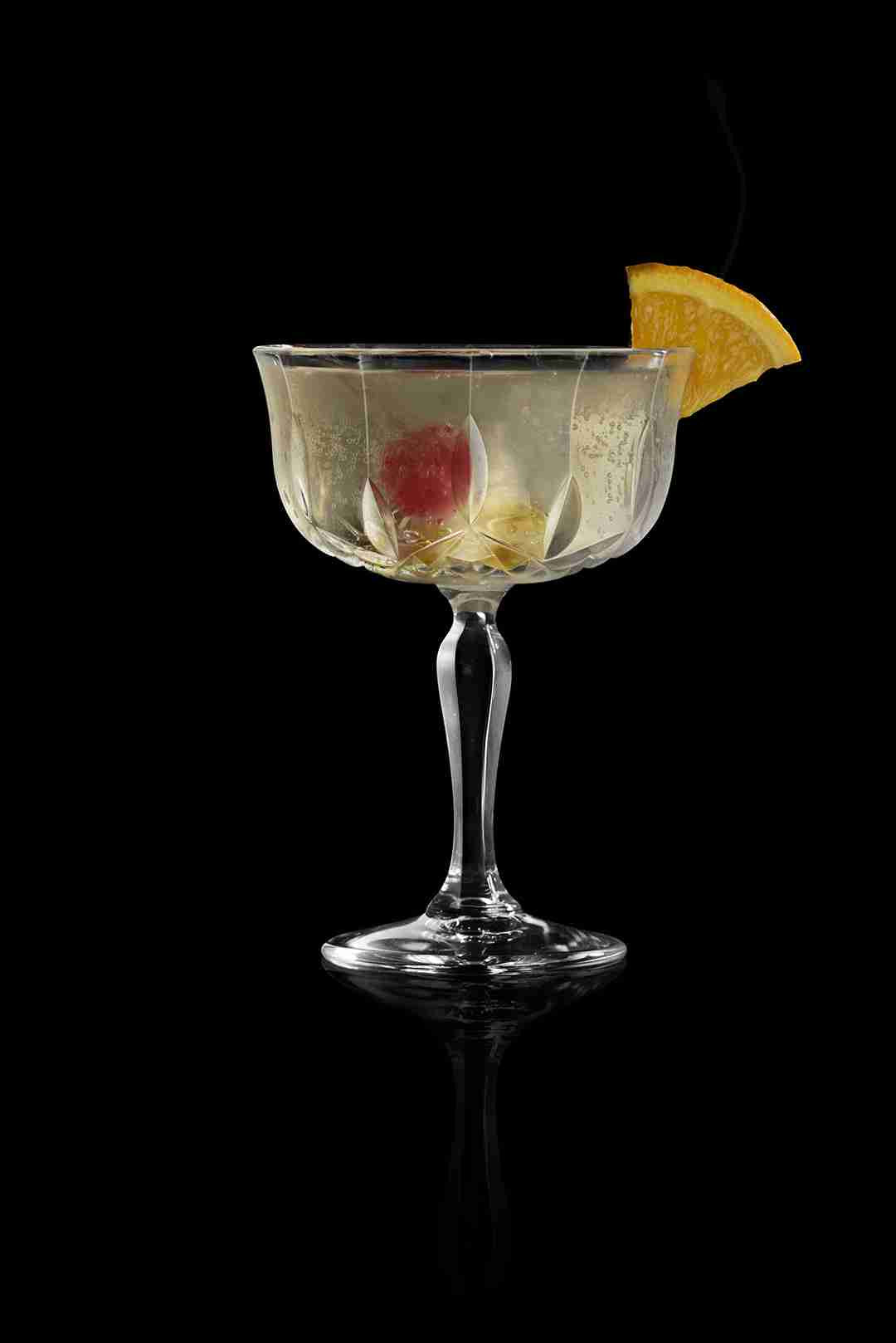 RCR Opera Champagne Goblet filled with a red cocktail against a dark, moody background