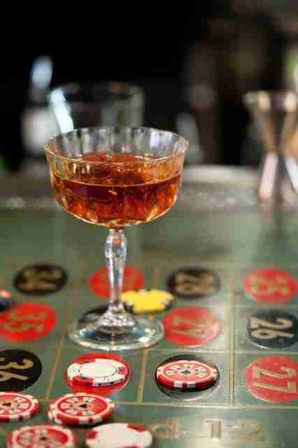 RCR Opera Champagne Goblet styled on a bar table with an amber cocktail