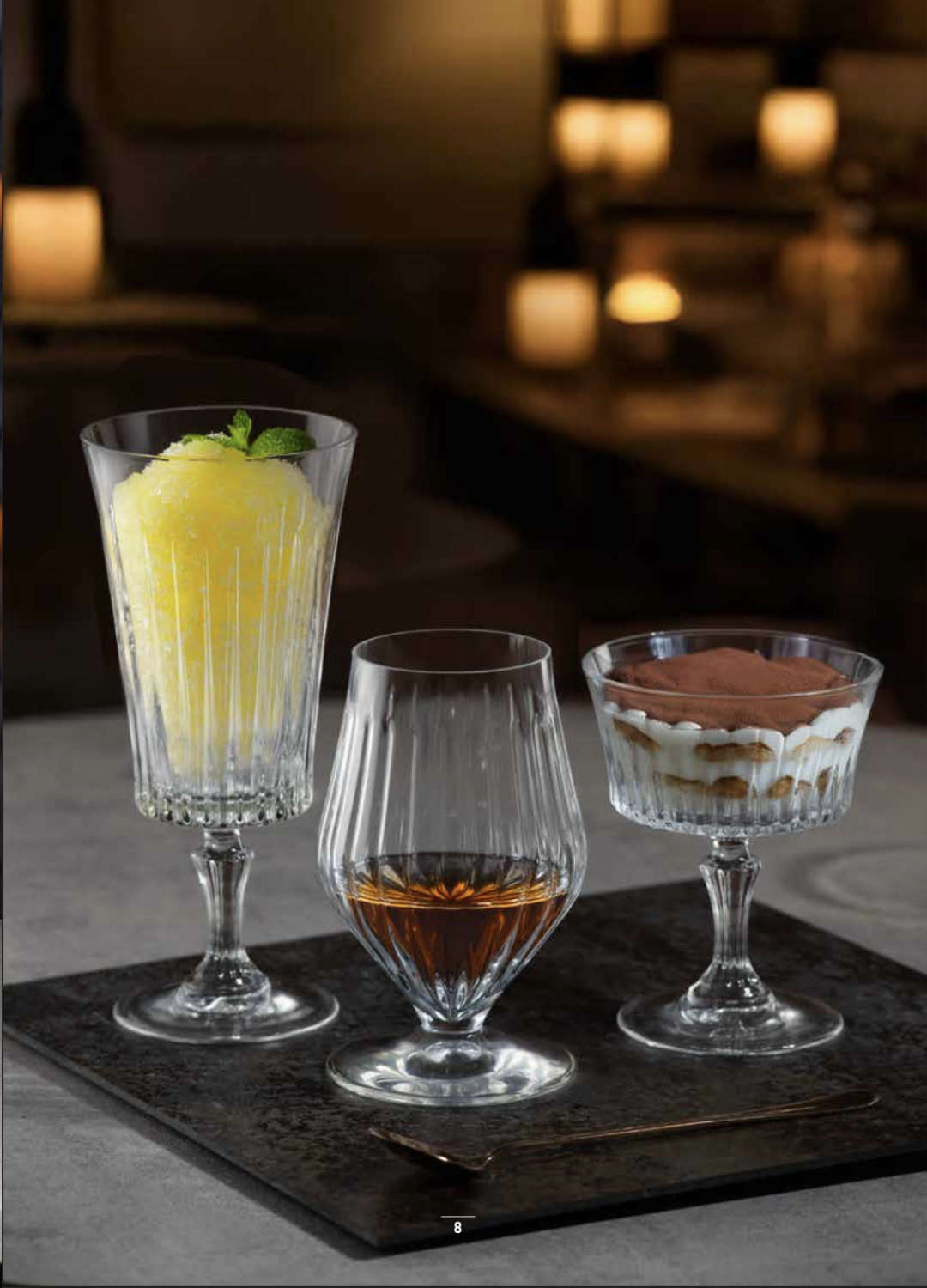 RCR Timeless Iced Beverage Glass filled with a lemon sorbet drink, styled alongside other Timeless glassware on a dark table setting